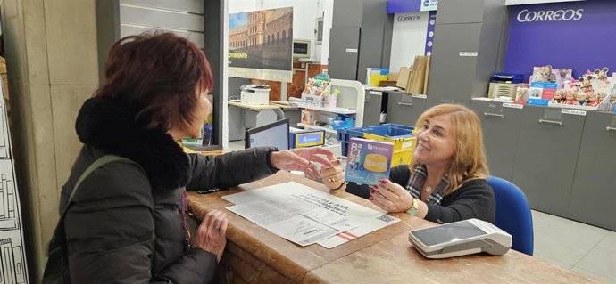 Una mujer adquiere una baliza V16 de la DGT en una oficina de Correos.