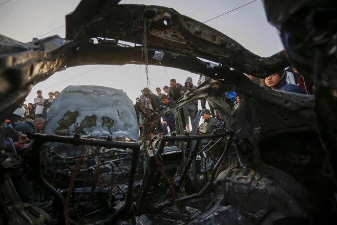 Un grupo de personas frente a los restos de un vehículo bombardeado por Israel en la Franja de Gaza (archivo)