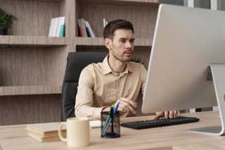 Archivo - Una persona trabajando con un ordenador en una oficina.
