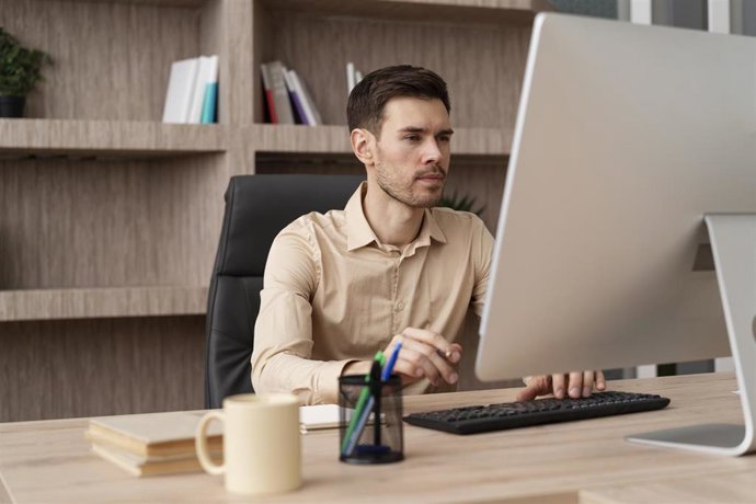 Archivo - Una persona trabajando con un ordenador en una oficina.