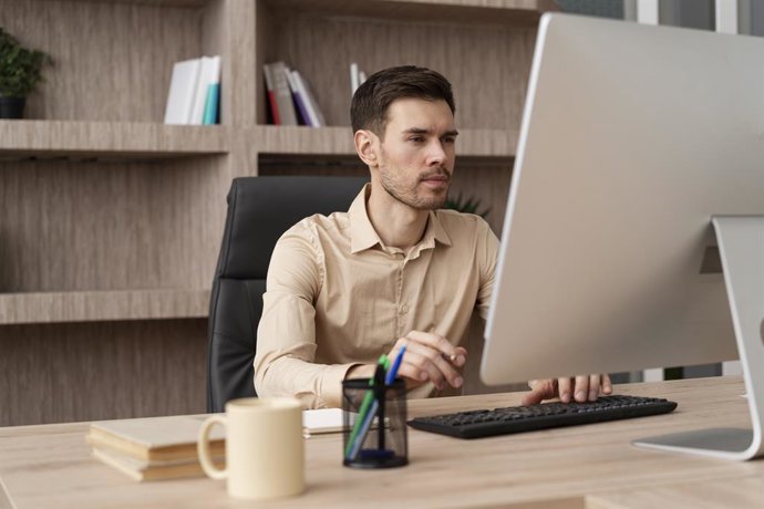 Archivo - Una persona trabajando con un ordenador en una oficina.