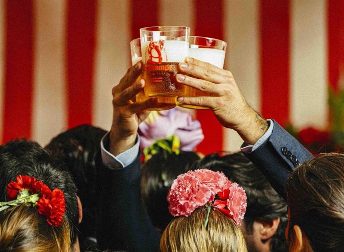 Imagen de recurso de un hombre que sostiene varias cañas de cerveza en el interior de una caseta de la Feria.