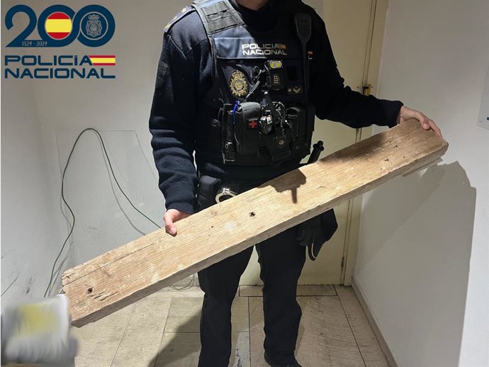 Un agente muestra el tablón de madera intervenido al arrestado.