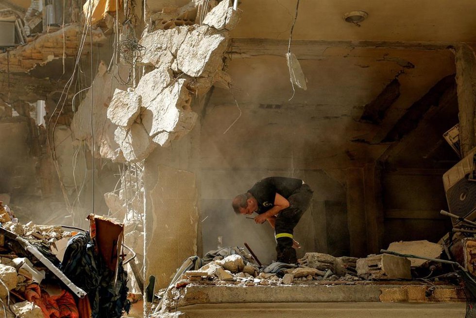 Miembro de la Defensa Civil Libanesa busca restos humanos bajo un edificio bombardeado por Israel en Beirut