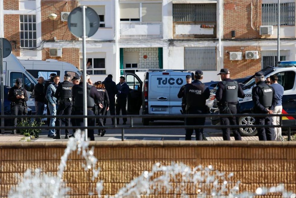 Agentes de la Policía Nacional junto a la furgoneta del tanatorio dispuesta para el traslado del cadáver de la mujer asesinada en el barrio de la Fuensanta.