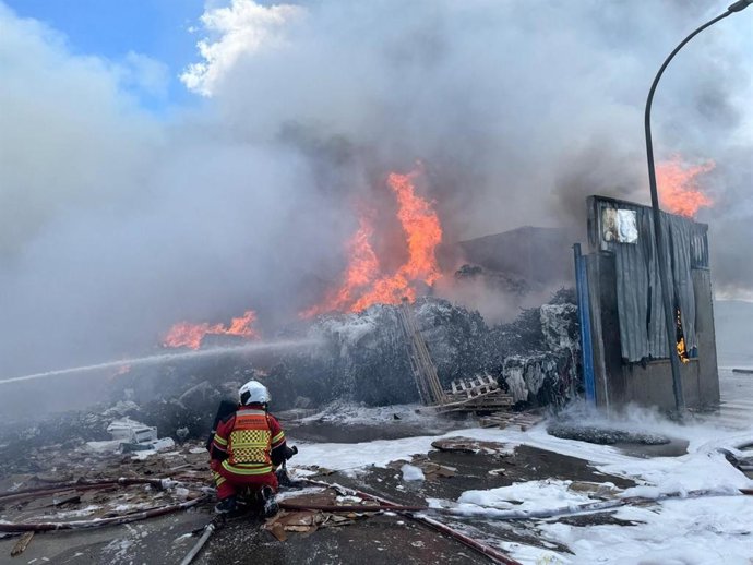 Un bombero de la Comunidad de Madrid atiende un incendio en una nave dedicada al reciclaje de cartón en Alcalá de Henares.
