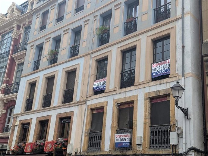 Edificio de pisos en Oviedo con varios carteles de venta de viviendas.