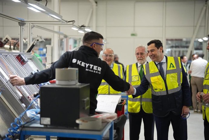 Juanma Moreno saluda a un empleado de Keyter durante su recorrido por las instalaciones de la multinacional en Lucena (Córdoba).