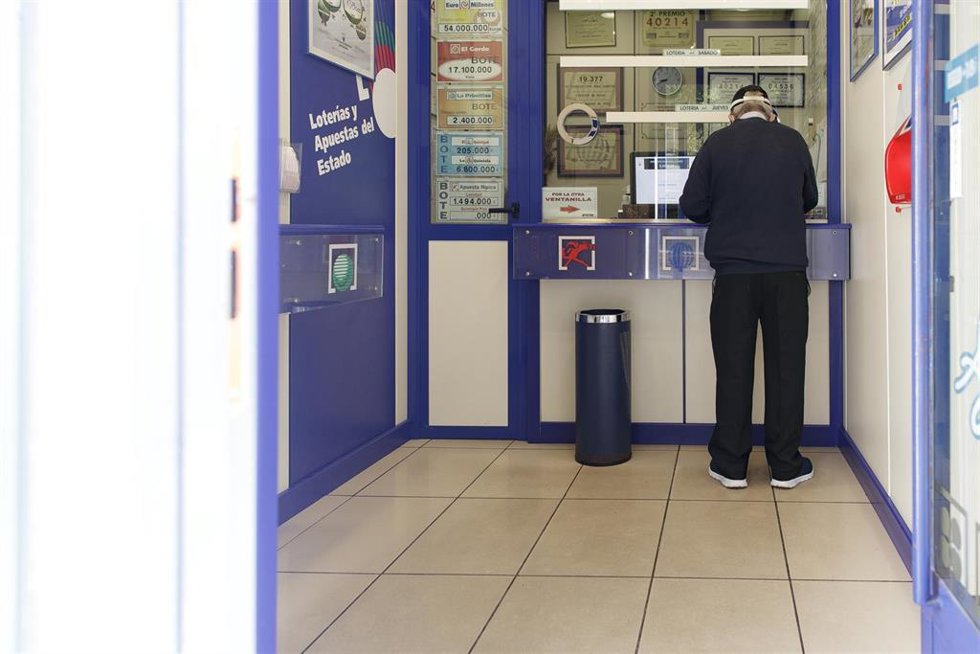 Archivo - Un hombre compra lotería en una Administración.