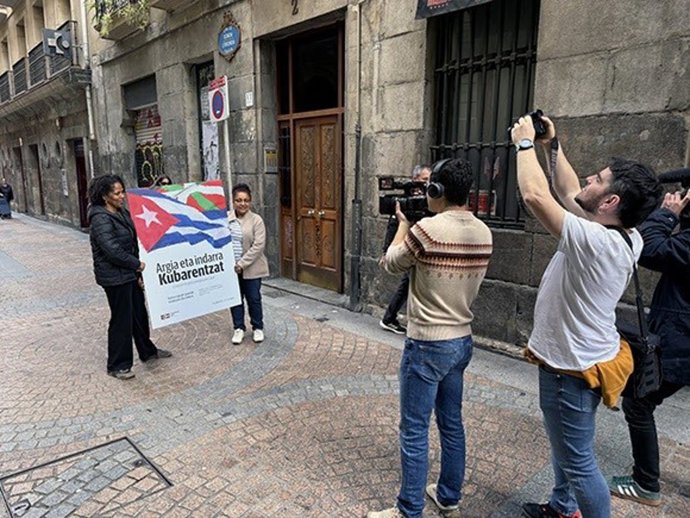Dos personas portan el cartel de la campaña 'Argia eta indarra Kubarentzat. ¡Contra el bloqueo, energía para Cuba!'
