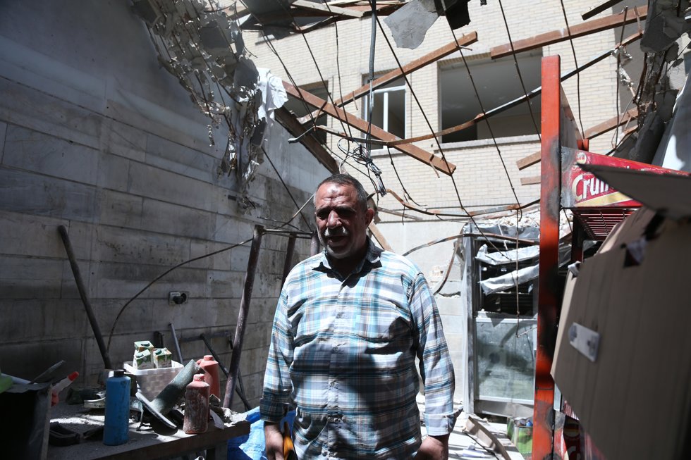 Un hombre en frente de su tienda destrozada por los ataques de Israel y EEUU en Teherán.