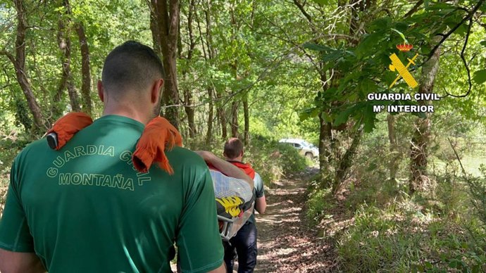 Agentes del Greim de la Guardia Civil llevan al herido en camilla.