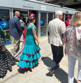 Mujeres vestidas de flamenca junto a una de las estaciones del Metro de Sevilla.