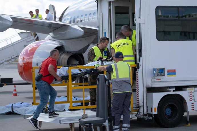 Operarios ayudan a un paciente a entrar en una ambulancia