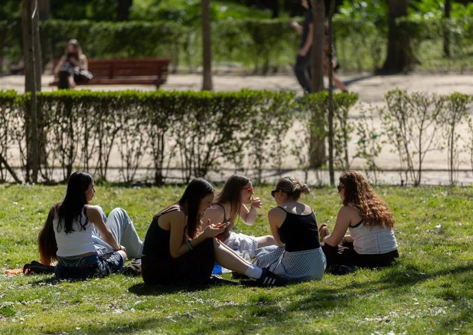 Un grupo de personas sentadas en el césped de un parque, a 17 de marzo de 2026, en Madrid (España).