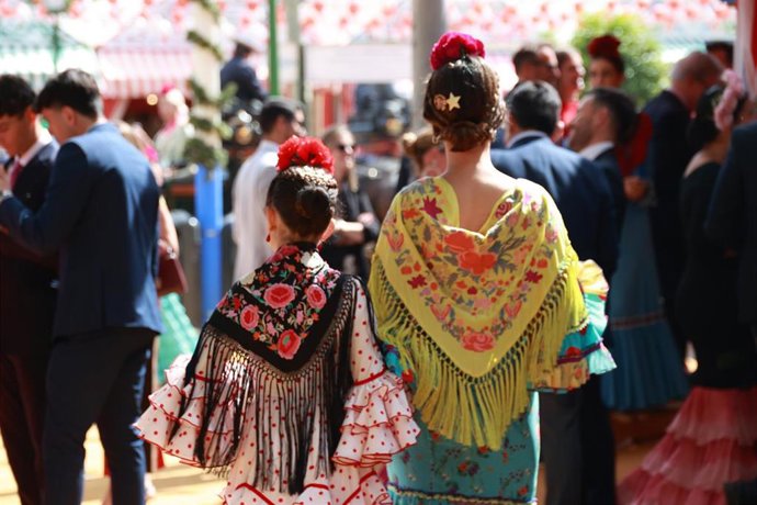 Archivo - Mujeres vestidas de flamenca pasean por el Real de la Feria de Abril de Sevilla. Imagen de archivo. 