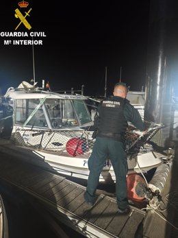 Un agente de la Guardia Civil con una de las embarcaciones intervenidas en San Fernando.