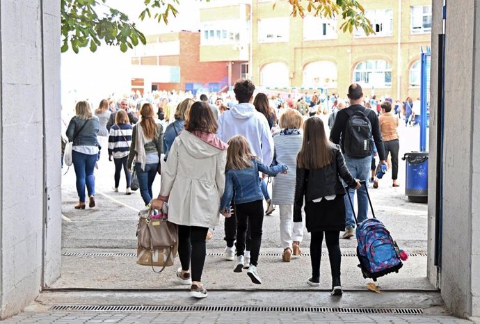Archivo - Niños entrando a un colegio junto a sus padres.