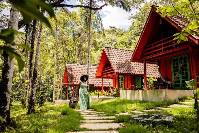 Archivo - Mid adult tourist woman walking with luggage and arriving on inn.