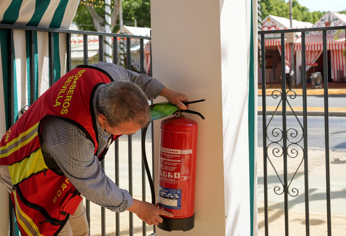 Miembros del cuerpo de bomberos de Sevilla realiza una inspección en una caseta de la Feria.