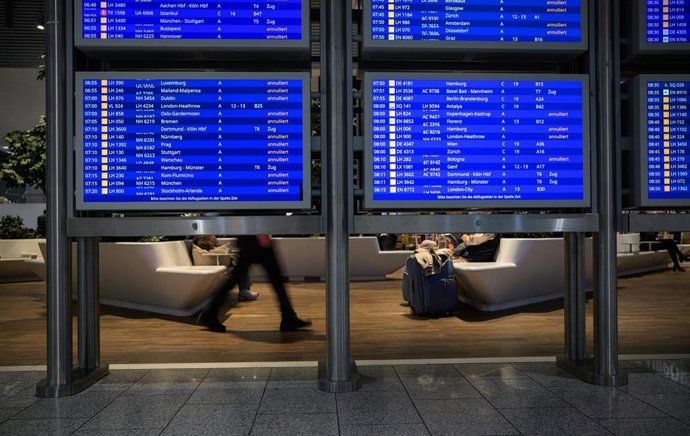 People sit in a waiting area behind display boards showing cancelled flights at Frankfurt Airport on the second day of strikes by the cabin crew union Ufo, while the pilots' union VC has announced full-day strikes at Lufthansa.