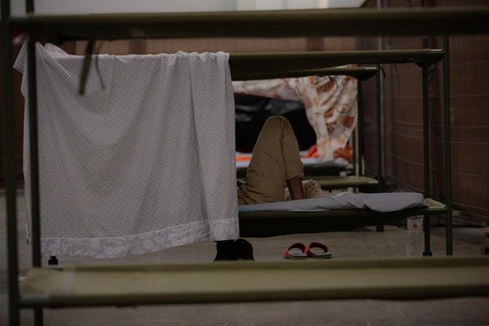 Archivo - Una persona descansa en su cama en el interior de las instalaciones del albergue de Fira Barcelona, habilitado en 2020 por la pandemia del coronavirus para 225 personas sin hogar.