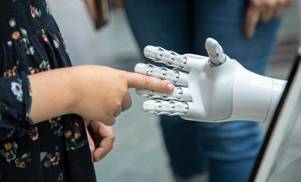 Recuso de niño tocando la mano de un robot