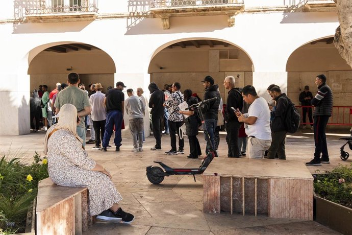 Personas migrantes hacen cola para la tramitación de su regularización administrativa frente al Ayuntamiento de Almería.