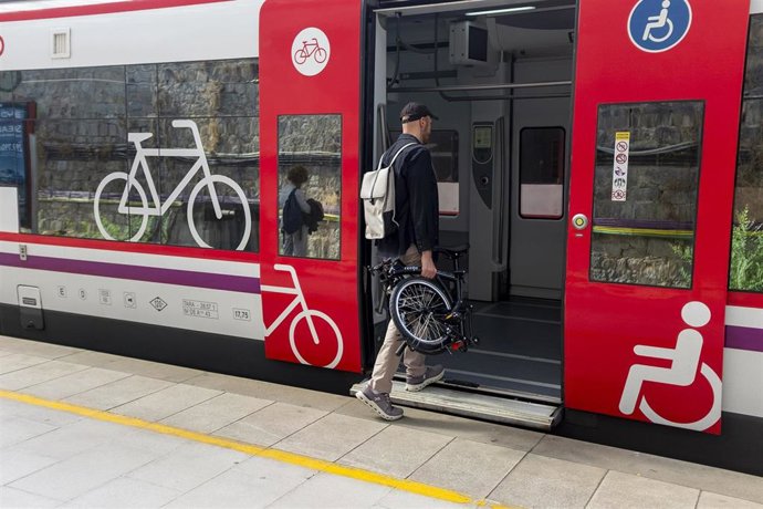 Archivo - Un usuario de Renfe entra a un tren de cercanías con su bici