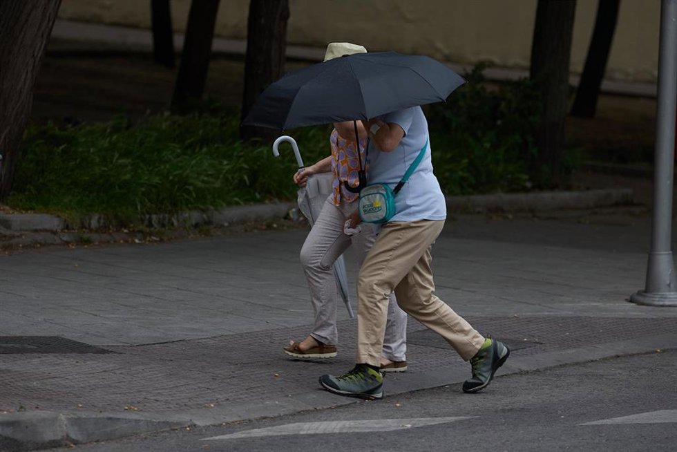 Archivo - Dos personas se protegen de la lluvia con un paraguas, a 8 de junio de 2024, en Madrid (España). 