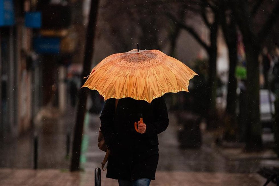 Archivo - Una persona se protege de la lluvia con paraguas, en Madrid (España).