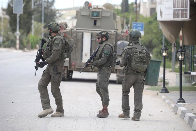 April 20, 2026, Tulkarm, West Bank, Palestine: Israeli soldiers take up positions in front of Israeli military tanks as they enter the town of Anabta, east of Tulkarm in the northern West Bank, during a raid in which several homes were searched for wanted