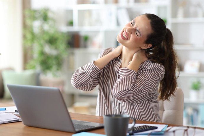 Archivo - Mujer trabajando en un ordenador con dolor de cuello.