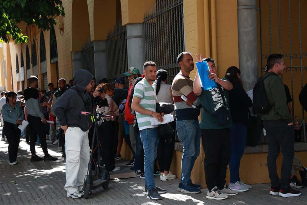 Personas migrantes hacen cola para la tramitación de su regularización administrativa en Sevilla.