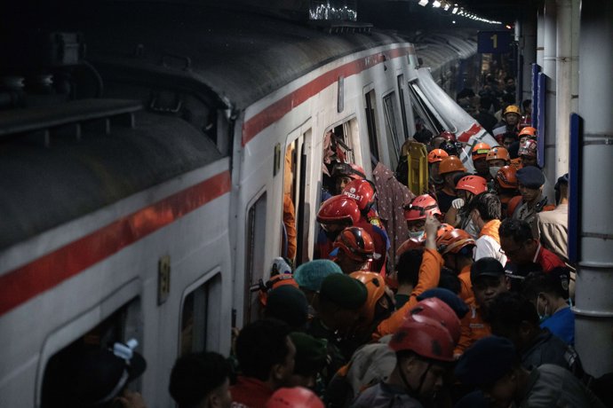 28 April 2026, Indonesia, Bekasi: people and first responders gather around a wrecked train after a collision occurred between two trains involving a Commuter Line train that was rear-ended by the Argo Bromo, a long-distance train bound for Java.