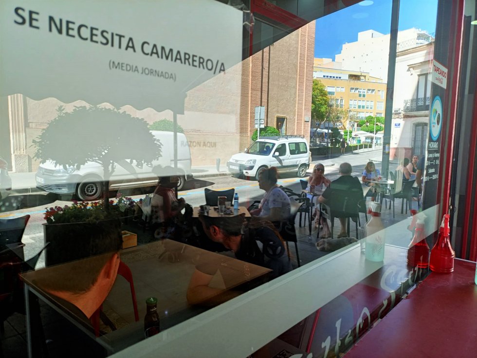 Cartel de 'Se busca camarero' en un bar con terraza.