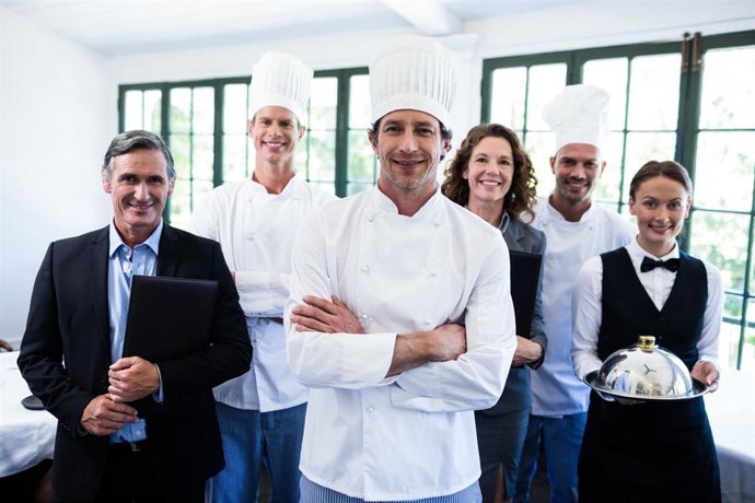 Archivo - Portrait of happy restaurant team standing together in restaurant