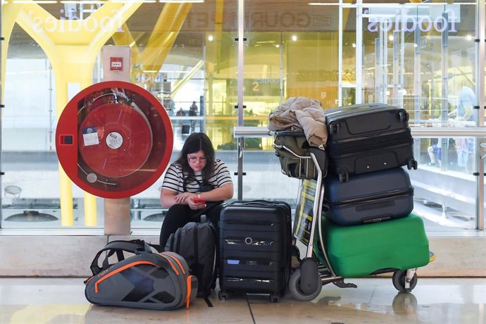 Archivo - Una viajera espera el embarque junto a su equipaje en una terminal de aeropuerto.