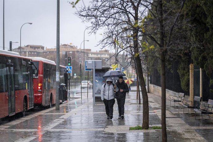 Archivo - Transeúntes por las calles de Granada en un día de tormenta. 