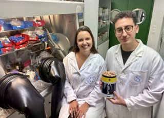 Los investigadores Azahara Cardoso y Omar Saad, que muestra un recipiente lleno de cáscaras de pistachos.