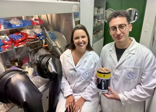 Los investigadores Azahara Cardoso y Omar Saad, que muestra un recipiente lleno de cáscaras de pistachos.