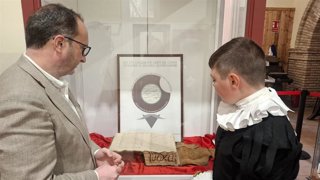 Ayala, junto a un escolar, observa el documento firmado por Cervantes.