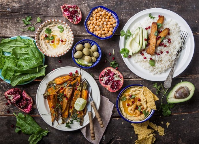 Archivo - Hummus, zanahorias asadas, arroz con tempeh en cuencos de cerámica vistos desde arriba, alimentos a base de verduras.