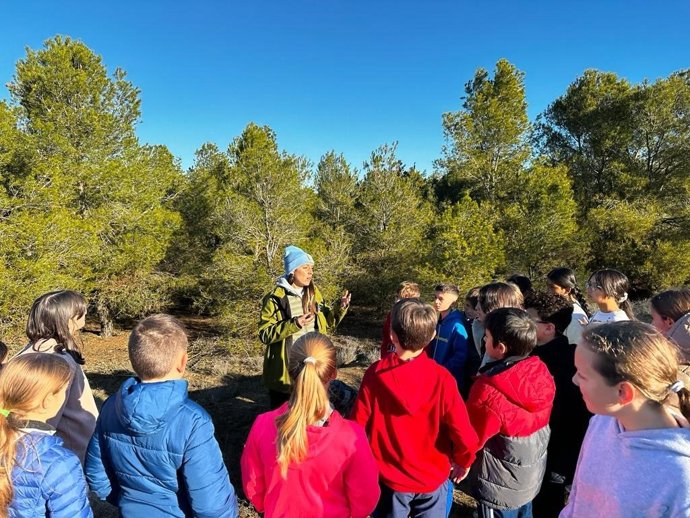 Jóvenes atienden a las explicaciones de una técnico en un espacio natural.