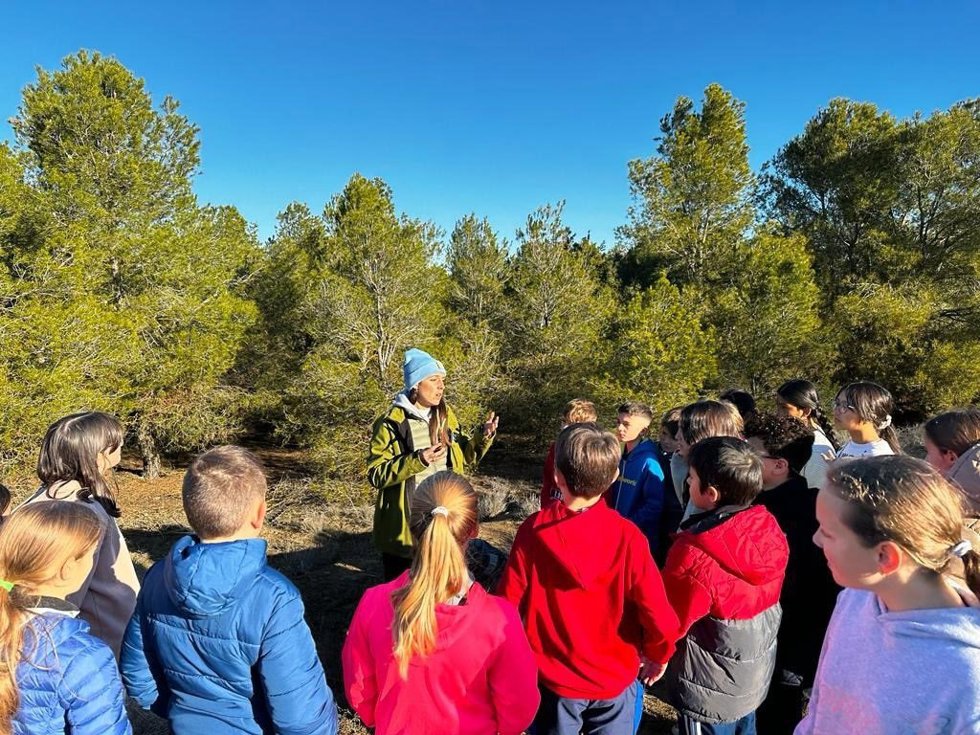 Jóvenes atienden a las explicaciones de una técnico en un espacio natural.