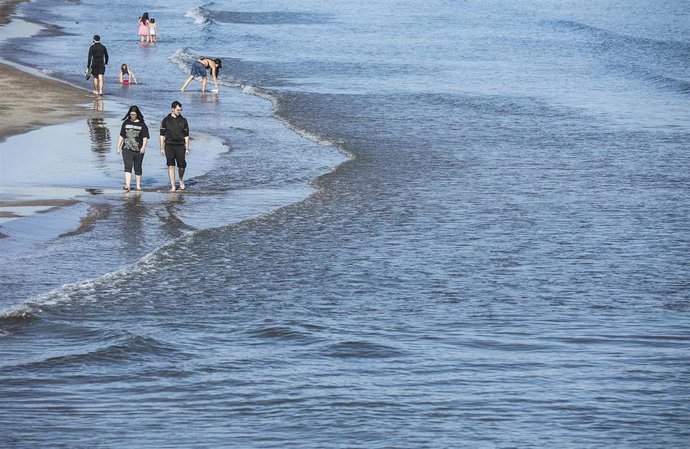 Archivo - Varias personas caminan por la playa de la Malvarrosa. 