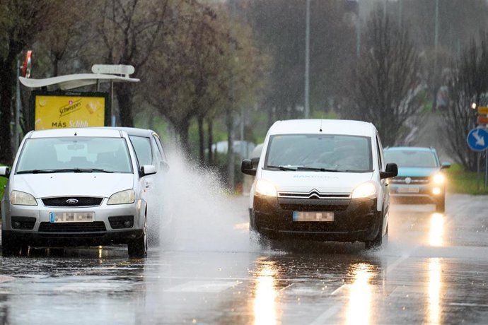 Archivo - Varios coches circulan por una carretera mojada