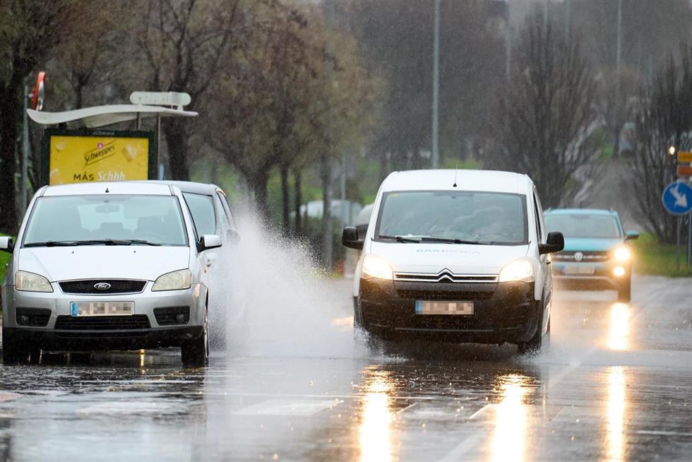 Archivo - Varios coches circulan por una carretera mojada