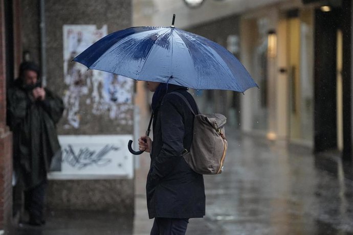 Archivo - Transeúnte por una céntrica calle de Sevilla bajo la lluvia.