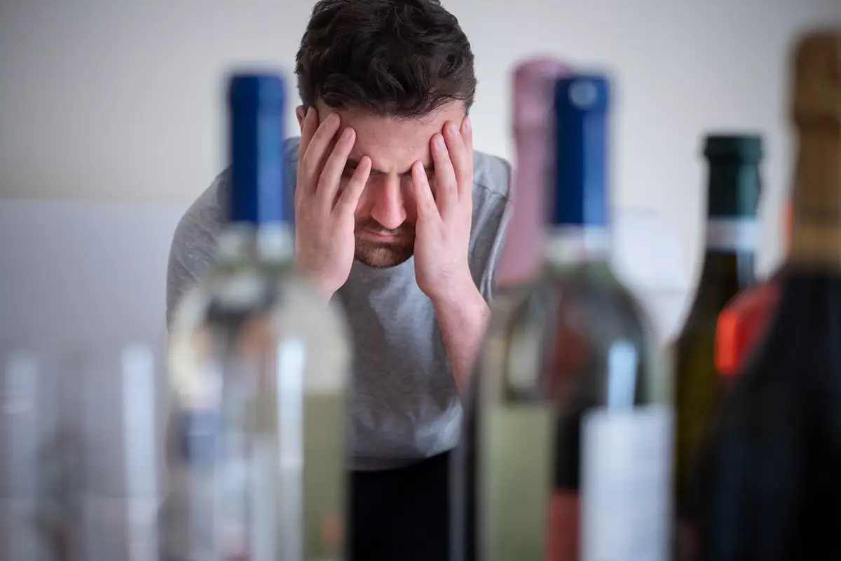 Hombre apesadumbrado antes botellas alcohólicas. - TOMMASO79/ISTOCK